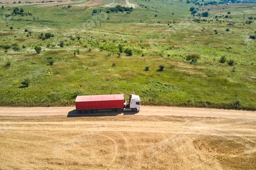 Preview: Aerial view of cargo truck driving on dirt road between agricultural wheat fields
