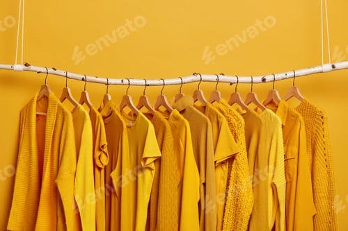 Preview: Rack with yellow clothes after dry cleaning. Wardrobe with various outfits for different seasons. Wo