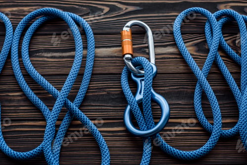 Preview: Isolated photo of climbing equipment. Parts of carabiners lying on the wooden table