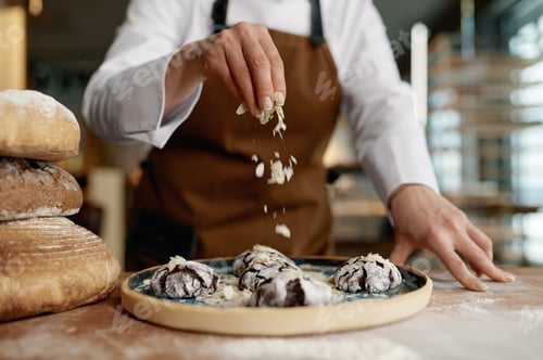 Preview: Baker chef sprinkling freshly baked oatmeal cookies with cereals