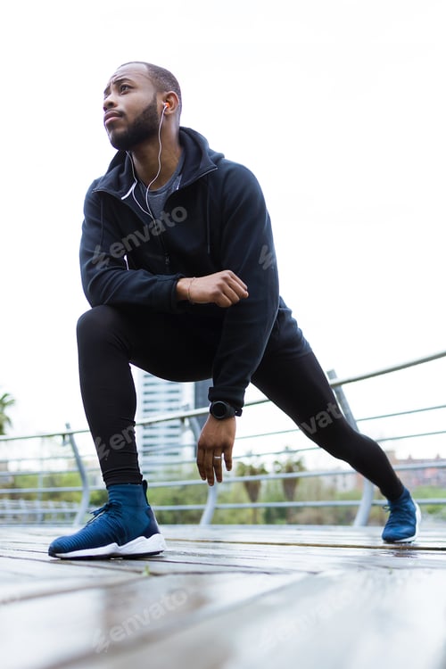Preview: Fit and sporty young man doing stretching in the city.