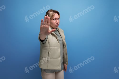 Preview: upset blond european lady in spring clothes with disagree gesture on blue background with copy space