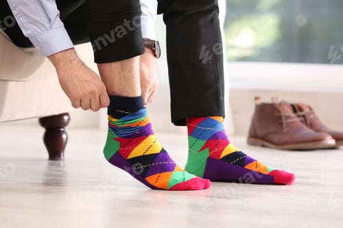 Preview: Man putting on stylish socks indoors, closeup