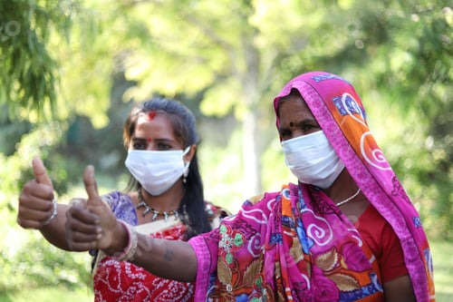 Preview: Portrait of two Indian women with thumbs up pose wearing a face mask before taking a covid-19 test