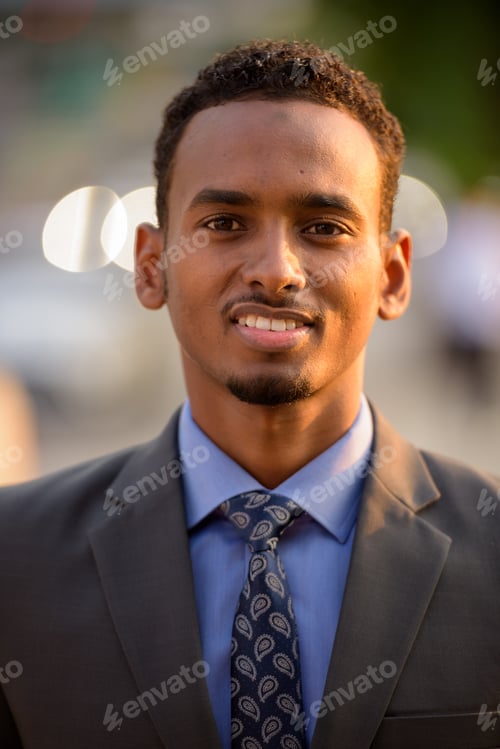 Preview: Handsome young black businessman face smiling in city
