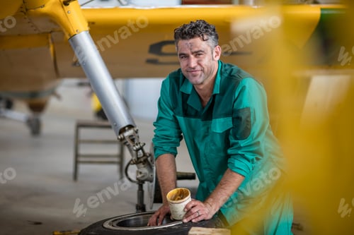 Preview: Mechanic in hangar lubricating landing gear of light aircraft