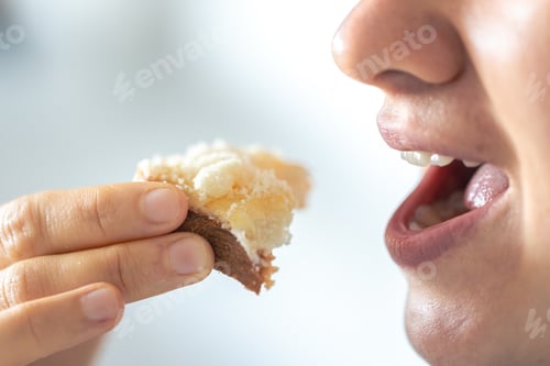 Preview: A woman eats bread with grated cheese, close-up.