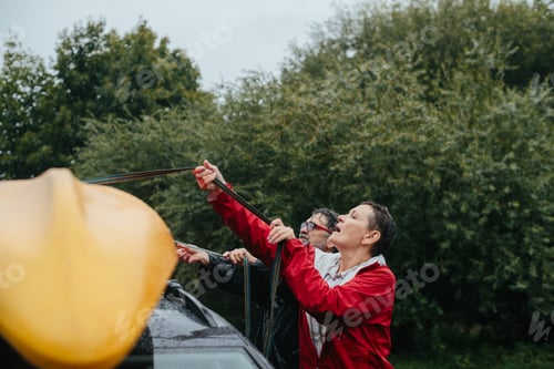 Preview: Senior couple securing kayak onto car roof during rain