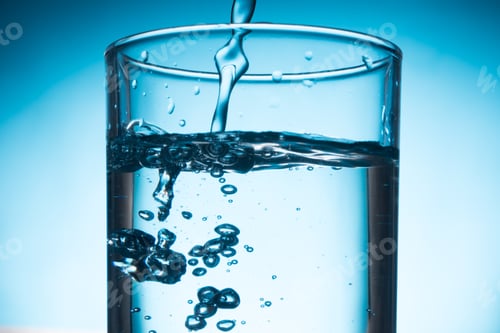 Preview: Pouring water into glass on blue background.
