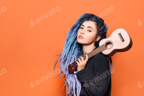 Preview: portrait of hipster woman with violet dreadlocks and ukulele in her hands on an orange background