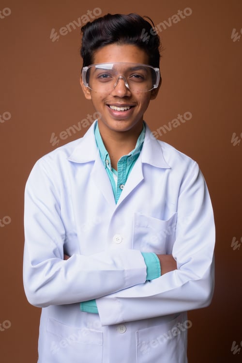 Preview: Young Indian boy doctor wearing protective glasses against brown