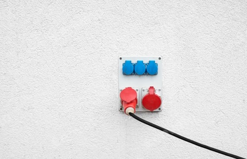 Preview: Industrial high voltage sockets mounted on a white wall.