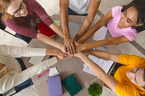 Preview: Multiracial teenagers joining hands together in cooperation
