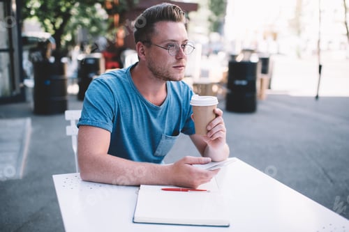 Man Sits at Table with Coffee and Notebook