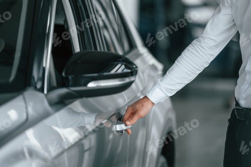 Preview: Opening the door. Young man in white clothes is in the car dealership