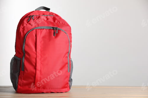 Preview: Red backpack on wooden table against light background. Space for text