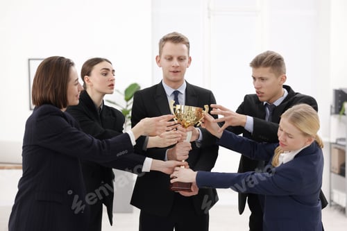 Preview: Competition concept. Group of businesspeople with golden trophy in office