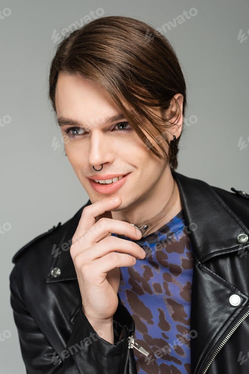 Preview: portrait of smiling bigender model with makeup and nose piercing wearing black leather jacket