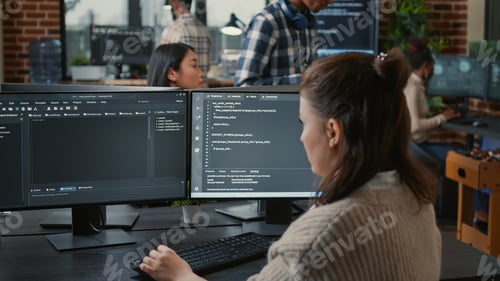 Preview: Software programer writing code in front of multiple computer screens
