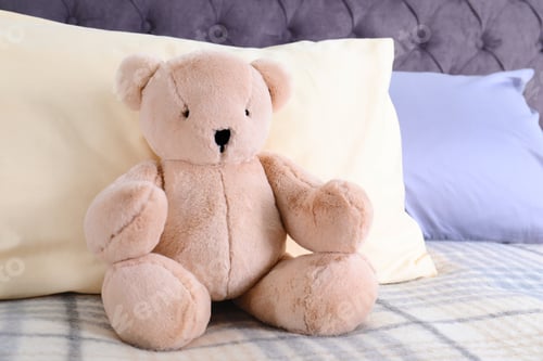 Preview: Cute teddy bear sitting on bed indoors. Space for text