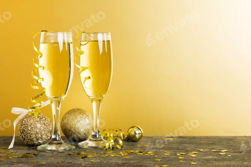 Preview: Champagne glasses and christmas decor on colored holiday background. Flat lay New Year decorations