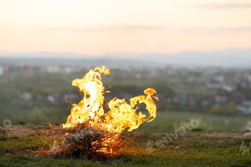 Preview: Big bright bonfire bugning at field in evening