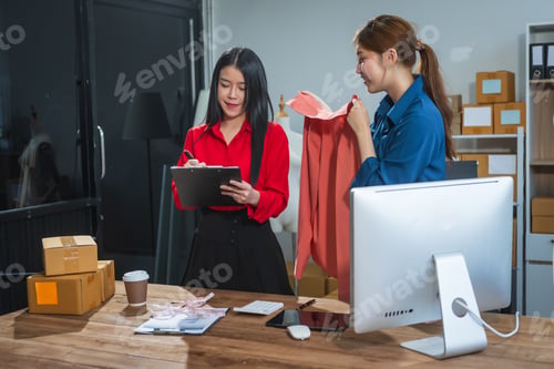Preview: Two Asian business woman work at desk, selling fashion clothes online.They packing checking items