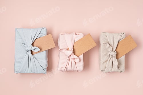 Preview: Zero waste gift wrapping traditional Japanese furoshiki style over pink background