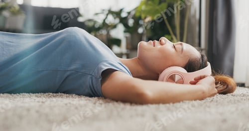 Preview: Woman with casual wear headphone lay down on carpet floor listen music calm.