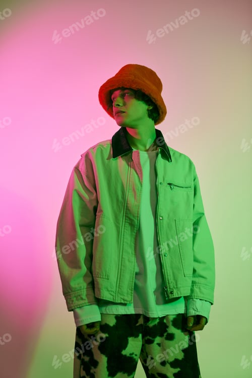 Preview: Young man showcasing contemporary fashion in a vibrant artistic studio setting during evening hours