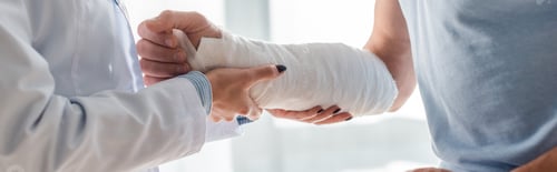 Preview: panoramic shot of orthopedist touching injured hand of man