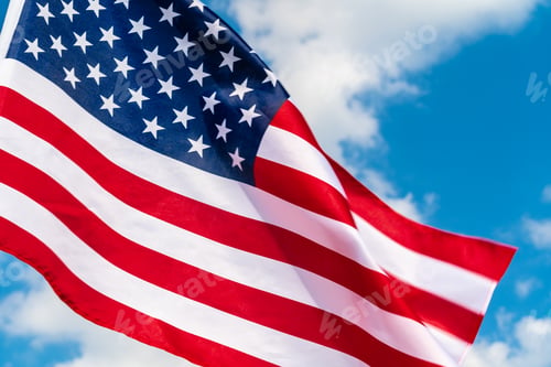 Preview: American flag waving in the wind against blue sky