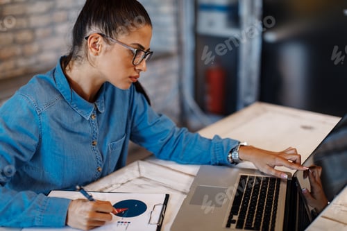 Preview: Young businesswoman taking notes from a laptop