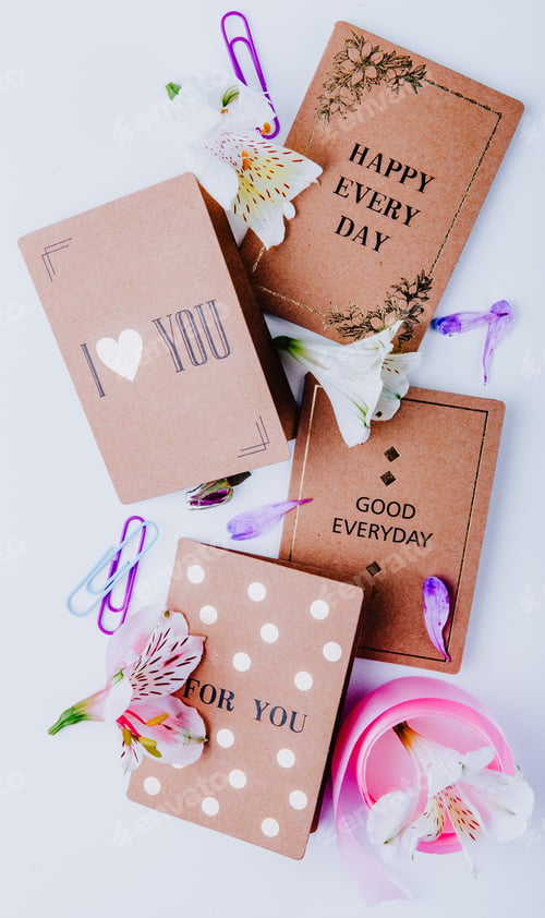 Preview: top view of various postcards paper clips and alstroemeria flowers on white background
