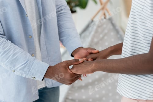Preview: cropped view of african american couple holding hands at home