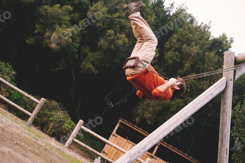 Preview: Adult man play and have fun flying high on swing at the park - happy aged people enjoying