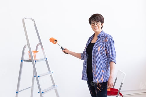 Preview: Middle-aged woman painting the walls of new home. Renovation, repair and redecoration concept