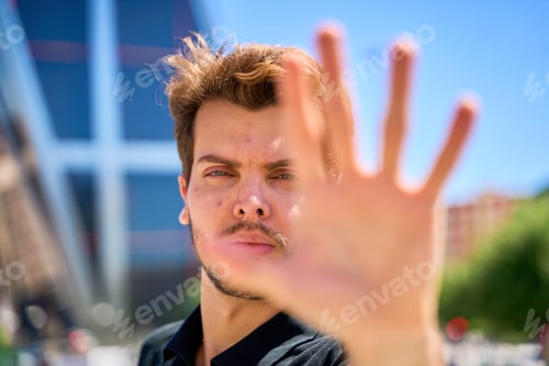 Preview: A man with a beard and mustache covers his face with his hand.