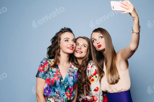 Preview: Happy friends in trendy clothes taking selfie over blue backgrou