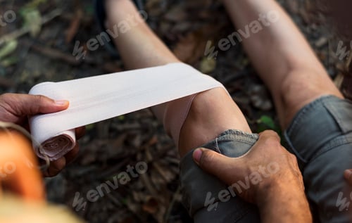 Preview: Man putting bandage on his partner's knee in the jungle