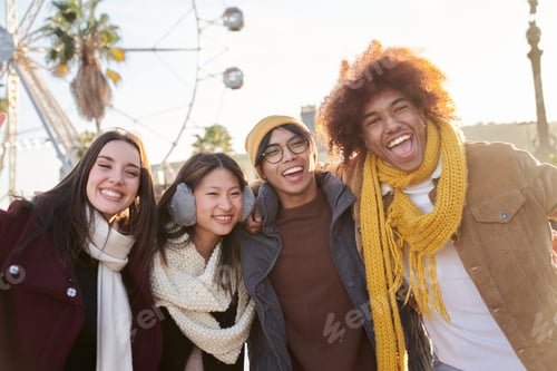 Preview: Group of four cheerful young friends posing for portrait in winter clothes. Students on field trip.