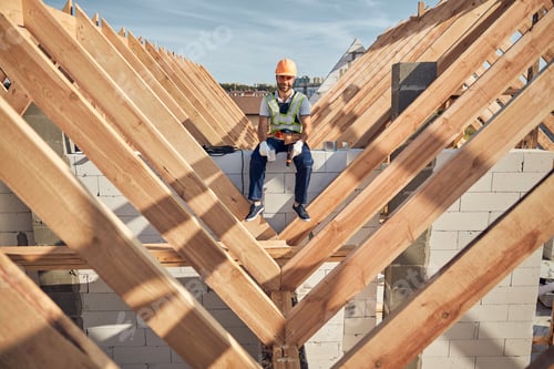 Preview: Cheerful male builder holding a drill while sitting