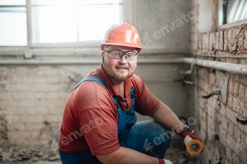 Preview: Builder in a protective helmet on a construction site working on a brick wall