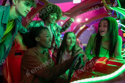 Preview: group of multiracial teenage friends in arcade playing car games with steering wheel