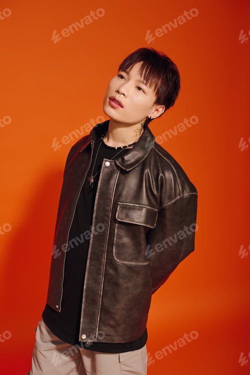Preview: Stylish young man exudes charm in a vibrant orange backdrop during a modern photoshoot