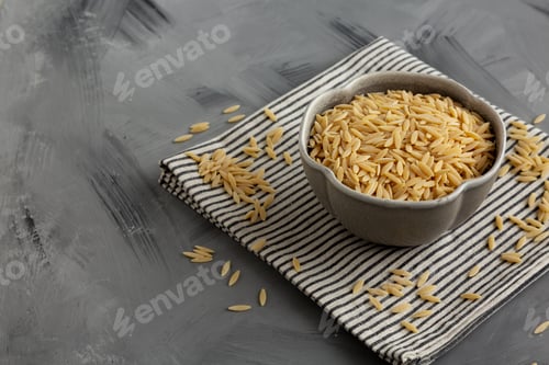 Preview: Raw Organic Orzo Pasta in a Bowl, side view. Space for text.