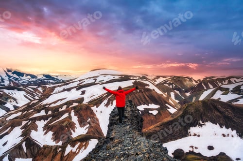 Preview: Hiker man standing on the cliff with volcanic mountain and snow covered view in summer