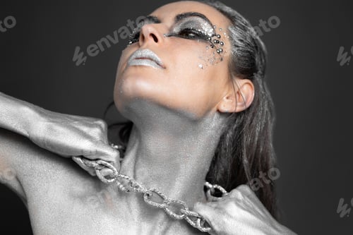 Preview: Beautiful woman with silver paint on her skin and hair breaks the chain around her neck.