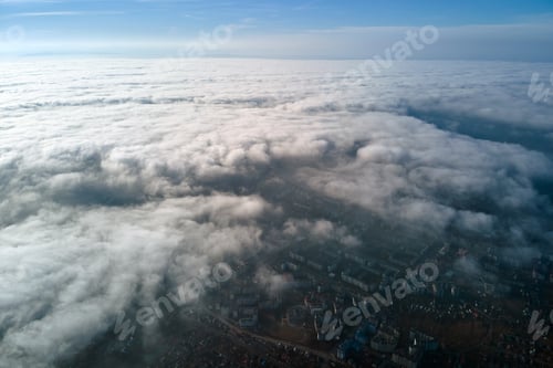 Preview: Aerial view from high altitude of distant city covered with puffy cumulus clouds