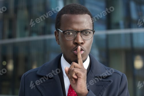 Preview: Classified african american executive points finger over lips asking for silence